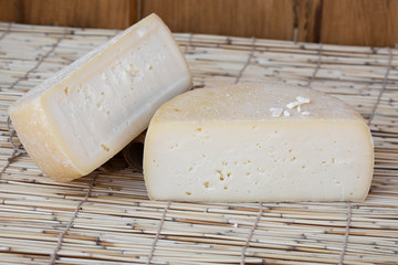 Two big organic cheese heads in the wooden background in the farm kitchen. Food concept. Farm cheese. Cheese Fair. Sliced round white homemade cheese - traditional milk creamy dairy product.