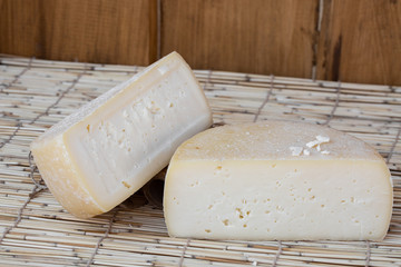 Two big organic cheese heads in the wooden background in the farm kitchen. Food concept. Farm cheese. Cheese Fair. Sliced round white homemade cheese - traditional milk creamy dairy product.