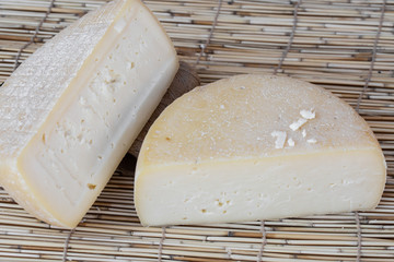 Two big organic cheese heads in the wooden background in the farm kitchen. Food concept. Farm cheese. Cheese Fair. Sliced round white homemade cheese - traditional milk creamy dairy product.