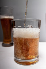 Closeup of pouring gold beer two on grey background for concept design. Summer concept.