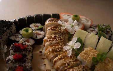 sushi rolls on a plate decorated with cherry flowers close up