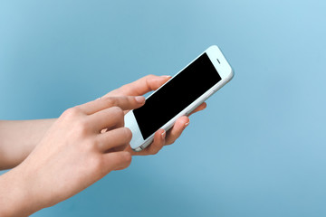 Female hands with mobile phone on color background