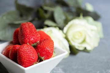  Fresh  strawberry on white bowl and white roses on the background.
