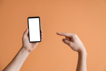 Male hands with mobile phone on color background