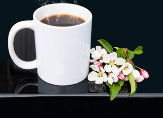 White coffee cup with cherry blossoms on a glossy black background in this styled product photo mockup.  Steaming hot black coffee with copy space on the mug for your text or designs.