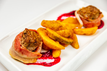 Fillet mignon rolled in bacon and baked in oven with berry sauce. Potato for garnish.