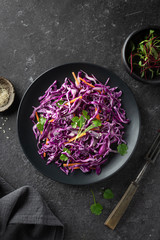 Red cabbage coleslaw with carrot on a dark background, top view. Healthy food concept. 