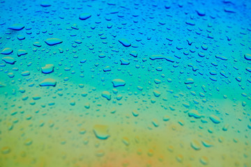 Water drops on the chameleon holographic surface. Beautiful colorful background with shallow depth...