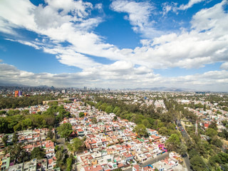 Fototapeta premium Vista aérea panorámica del sur de la Ciudad de México con un cielo nublado como fondo.
