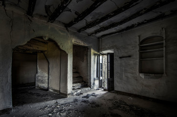 Habitación sucia con puertas en la penumbra de casa de campo abandonada en ruinas. 