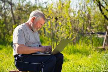 Elderly man with a laptop in village