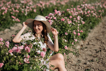 Portrait of a beautiful girl on the background of a bush of rink roses. 