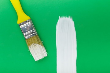 yellow paint brush and white stroke on a green background close up