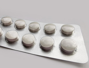 White pills in pack on light gray background. Disease treatment. The fight against coronavirus 2020.