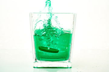 green water splash in glass with lemon slice