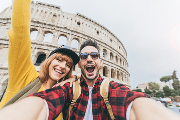 Fototapeta na wymiar Happy couple of tourist having fun taking a selfie in front of Colosseum in Rome. People travel Rome, Italy.