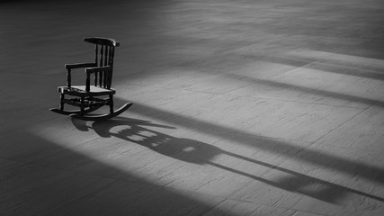 Sunlight and shadow on surface of  the old vintage little wood rocking chair on wooden tile floor...