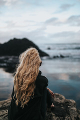 girl on a rock on a black beach