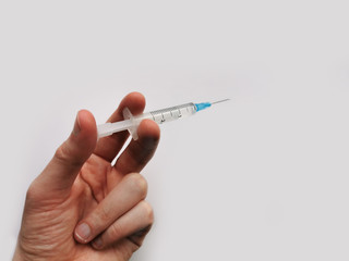 Syringe with medicine in a hand on a gray background. Treatment of diseases. The fight against coronavirus 2020.