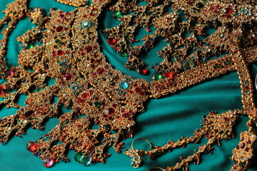  Indian jewelry on a green Sari background. Two Indian necklaces with multicolored gems.
