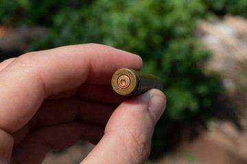 
Man holds sleeve from pistol bullet