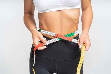 Woman checks waist with scale by soft tape measure or tape line