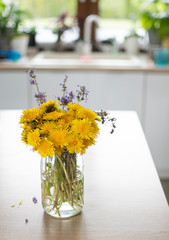 Bukiet żółtych polnych kwiatów stojący w kuchni w dziennym jasnym świetle - obrazy, fototapety, plakaty
