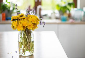 Bukiet żółtych polnych kwiatów stojący w kuchni w dziennym jasnym świetle - obrazy, fototapety, plakaty
