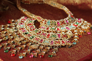  Indian luxury jewelry on a red Sari background. Two Indian necklaces with multicolored gems.