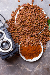 An old camera, roasted coffee beans and ground coffee on a marble table