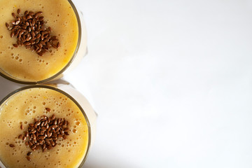 Orange-banana smoothie on a white table with copy spase