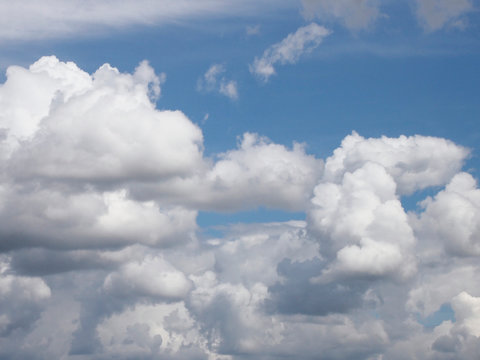 View of the blue sky with thick white clouds. Dense cumulus cloud cover. Summer day, nature. Soft focus. Artificial noise.