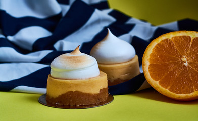 Dessert meringue, citrus tart on a lemon background with an orange striped cloth. Delicious sweets and pastries. Tartlet.
