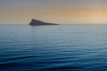 Isla en un mar en calma durante un atardecer