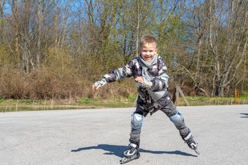 Happy boy learning to ride roller skates on a sunny day.