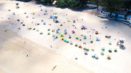 Aerial view of the white sand beach full of umbrellas and people resting during their holidays in Shek O Village, Hong Kong 