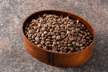 Roasted coffee beans in a wooden box on a dark background.