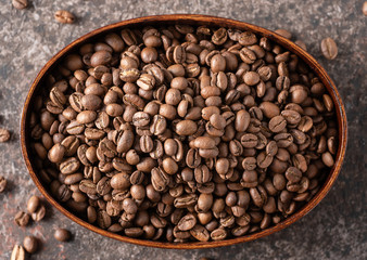 Roasted coffee beans in a wooden box on a dark background.