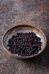 Sublimated blueberries in a brown ceramic plate on a dark background.