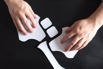 Hands arranging on synthetic leather paper templates; making a homemade mask