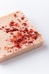 A bar of white chocolate with freeze-dried strawberries on a white background.