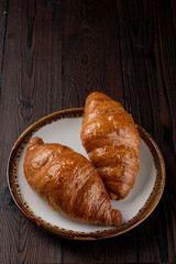 Baked fluffy croissants with golden crispy crust on wooden table, top view