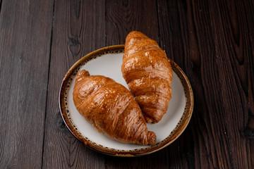Baked fluffy croissants with golden crispy crust on wooden table, top view