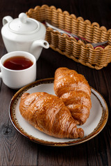 Baked fluffy croissants with golden crispy crust on wooden table, top view
