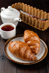 Baked fluffy croissants with golden crispy crust on wooden table, top view