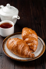 Traditional french croissants of puff-dough and butter on dark wooden table