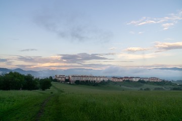 Sunrise and sunset, beautiful clouds over the meadow, hills and buildings in the town. Slovakia