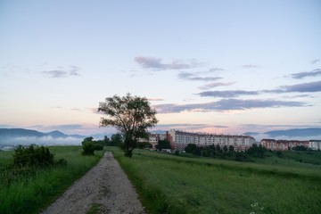 Sunrise and sunset, beautiful clouds over the meadow, hills and buildings in the town. Slovakia