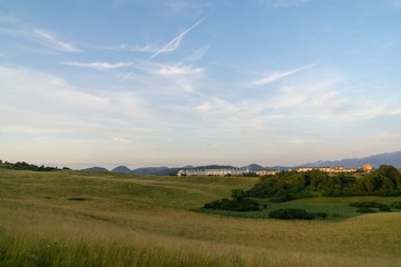 Fototapeta premium Sunrise and sunset, beautiful clouds over the meadow, hills and buildings in the town. Slovakia