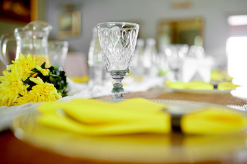wine glass and plate on which there are appliances and covered with a yellow festive napkin